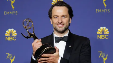 Reuters Matthew Rhys, in black tie, smiles at the camera with the Emmy he won in 2018