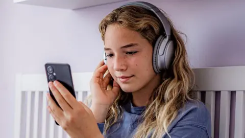 A young girl looks at a smartphone