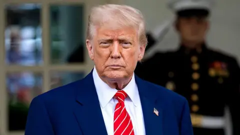 President Donald Trump in a dark suit and red tie 