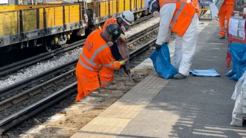 Men in hiviz are removing slabs from a platform