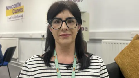 MOLLY SMITH / BBC NEWS Lisa Mollett has dark black hair and is wearing a black and white top, with a green lanyard around her neck. 