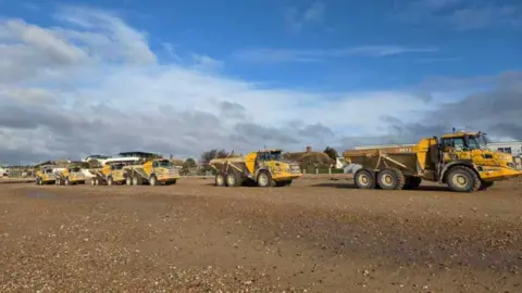 Environment Agency A number of yellow tipper trucks in a row.