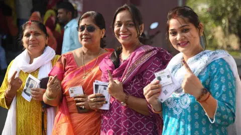Getty Images Four women pose outside a polling station in Bihar's Patna pose for a photograph after casting their votes
