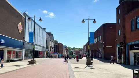 A photograph of a high street with shops either side and looking quite empty 