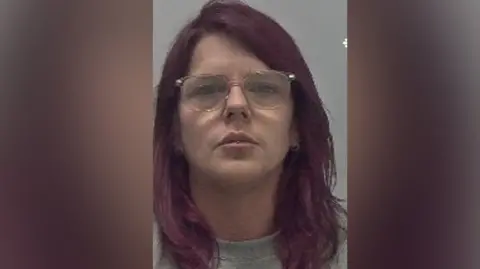 West Mercia Police A woman with red hair and glasses wearing a grey top against a grey background