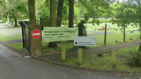 Google The gated entrance to Easthampstead Park Cemetery and Crematorium. A road runs through to the cemetery, and a field of gravestones can be seen in the background