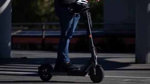 Getty Images An individual riding an e-scooter on a road but can only be seen from the waist down