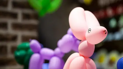 Getty Images A pink balloon animal with big ears and a red nose