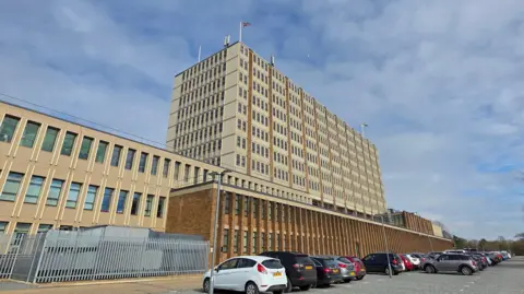 Paul Moseley/BBC We can see the main section of Norfolk's County Hall - a multi-storey brutalist building - which is a mixture of grey and beige.