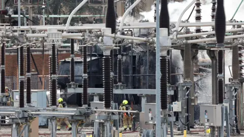 Reuters Smoke rises as firefighters work at the area of an electrical substation, after a fire there wiped out the power at Heathrow International Airport, in Hayes, London, Britain, March 21, 2025.