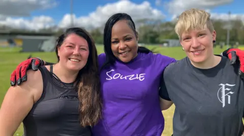 Shariqua Ahmed/BBC Leila Blake, Suzie Shamu and Kim Sommerman, standing next to each other smiling for the camera. 