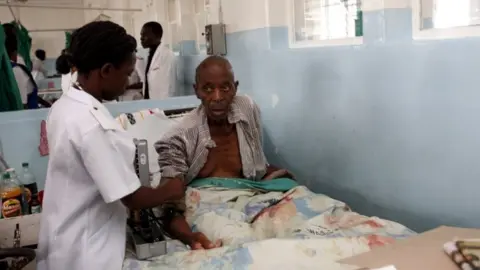 AFP An elderly patient receives treatment from a nurse while sitting up in bed at Harare central hospital (28 February 2009)