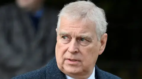 A head and shoulders image of a man with grey hair and brown eyes looking off to his right. He is wearing a blue herringbone jacket
