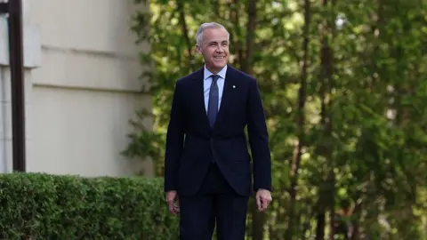 Mark Carney, Canada's prime minister, wearing a dark blue suit and tie and smiling broadly, arrives for a swearing-in ceremony at Rideau Hall in Ottawa, Canada