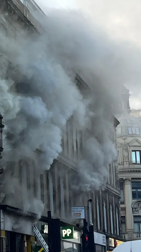 Joe Diaz A tenement building with clouds of smoke pouring out of the windows