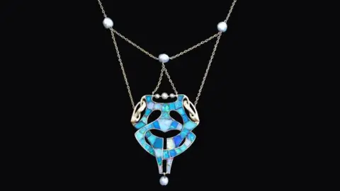 MNH An opal pendant, which has intertwined blue colours on a silver chain, against a black background.