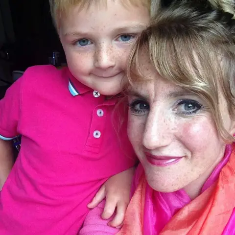 Sam Hey Hamish cuddles into his mum Susan for a photo. They are wearing bright pink clothes and are smiling.