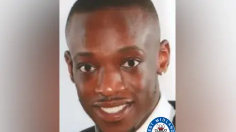 A close up of man's face. He has short neat hair and a trimmed moustache. He is smiling at the camera