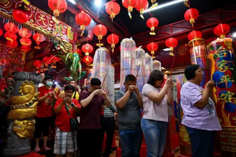 Juni Jriswanto/AFP People stand inline holding incense as they pray at the Hong San Koo Tee temple in Surabaya 
