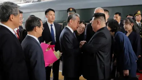 KCNA picture released by the Korean Central News Agency on September 2, 2025, shows North Korean leader Kim Jong Un walking (top), and being greeted next to his daughter Kim Ju Ae by Director of the General Office of the Chinese Communist Party (CCP) Cai Qi (bottom left) and Chinese Foreign Minister Wang Yi (bottom right), after his arrival in Beijing, China.