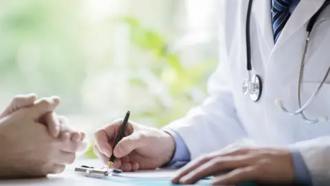 BrianAJackson via Getty Images Doctor and patient taking notes in medical surgery