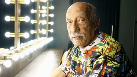 A head and shoulders shot of Mulatu Asatke wearing a patterned shirt