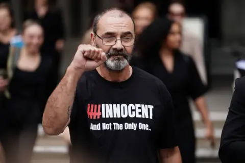 PA Media Andrew Malkinson stands with a clenched fist