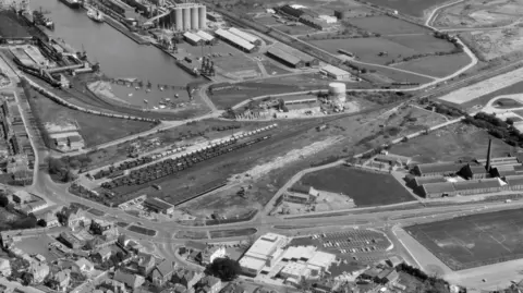 Heritage Images Old archive aerial shot of Portishead. There's the docks and power station around the water. There's a clear road going into the town and then a line where the railway track was.