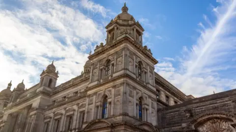 The large Glasgow City Chambers building, on a sunny day. The building has towers stretching into the sky.