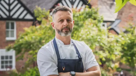 Moor Hall Mark Birchall in his chef whites and dark apron outside Moor Hall, which has a Tudor black and white roof