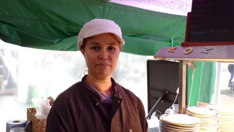 Matt Knight/BBC A woman at a street food stall in Chelmsford Market