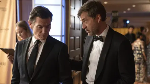 Apple TV+ Billy Crudup plays Cory Ellison, the ratings-obsessed president of UBA's News Division, with Mark Duplass, who is Charles Black, The Morning Show's stressed executive producer