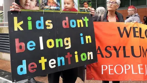 Getty Images A man holds a sign saying kids don't belong in detention