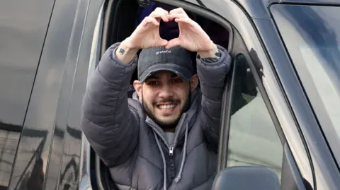 Reuters Eliya Cohen smiles after being released on February 22. He is holding up his hands to form a heart symbol