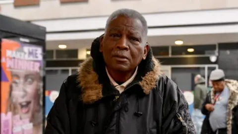 Helen Mulroy/BBC Jocelyn Lendore looks directly at the camera and wears a black jacket with brown fur collar. 