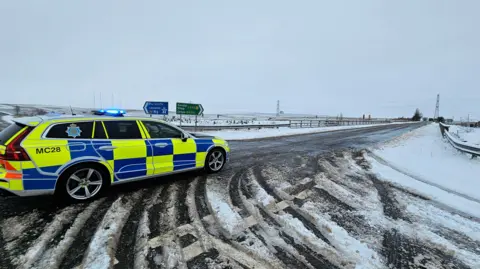 Cumbria roads police & firearms support unit A Cumbria Police car with is blue lights on on a snowy road.