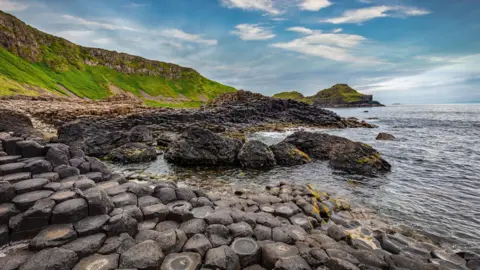 Getty Images The volcanic stones that make up the giants causeway, seen on a sunny bright day, with the sea on one side and rolling hills on the other