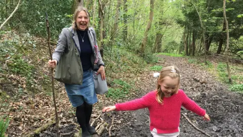 Family handout/PA Media Alison Clark and her daughter Emily playing in a forest. They both look happy.