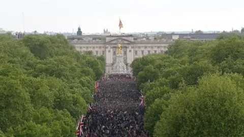 PA Media Members of the public walk up The Mall following a military procession marking the 80th anniversary of VE Day