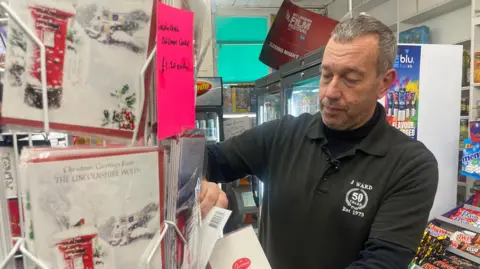 Sub-postmaster David Ward restocks the Lincolnshire Christmas cards on sale at East Barkwith Post Office 
