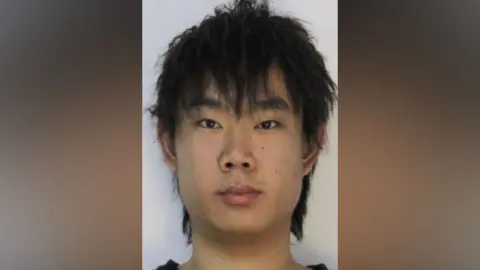 Mugshot of Li. He is clean shaven with neck-length, thick black hair.