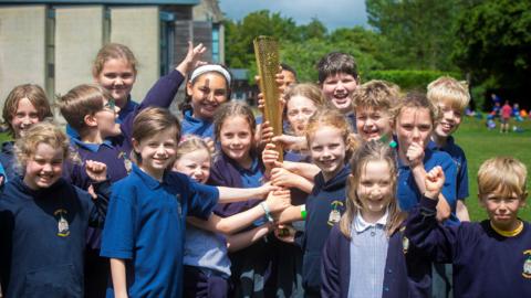 A group of primary school pupils outside holding the London 20212 Olympic torch
