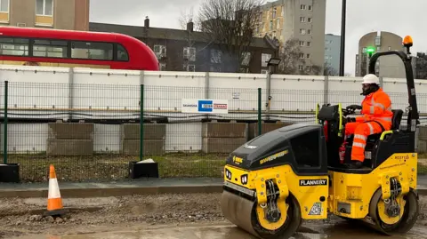 A man sits on a roller truck on a construction site