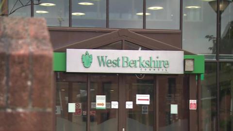 The exterior of West Berkshire Council Offices, including a large glass facade and a silver sign with the council's name in green letters.