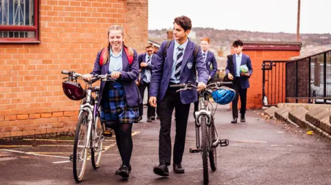 Getty Images A group of school children arriving in the school yard with their bikes