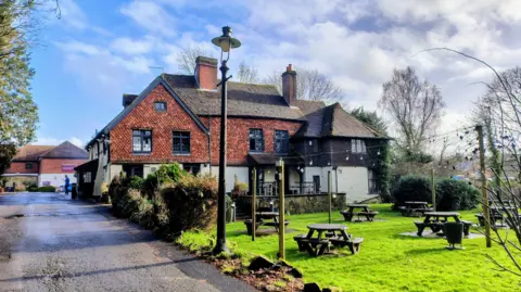 Simon Furber/ BBC A restaurant building with a pub garden adn benches in front of it.