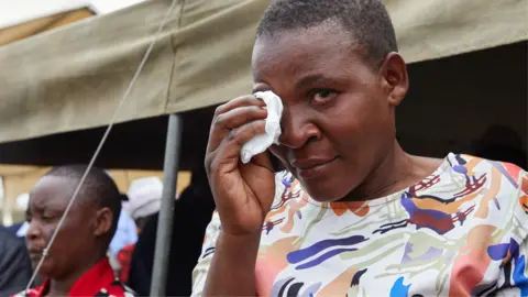 A female survivor uses a tissue to wipe tears from her eyes during a memorial service held for victims of the capsized ferry at Nyamhunga Stadium in Kariba - 13 August 2026