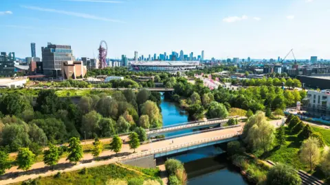 The 2012 Olympic Park with the stadium at the centre of the image and skyscrapers in the distance. 