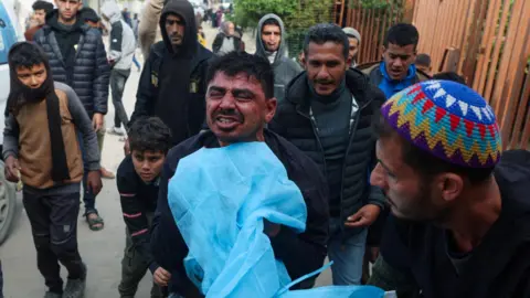 Reuters A Palestinian man mourns his son, Mutasem al-Shrafi, who was killed by Israeli fire in Khan Younis, in the southern Gaza Strip (21 January 2026)
