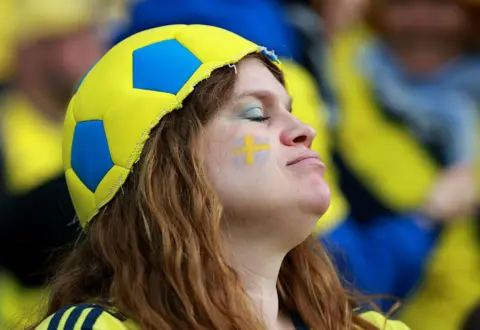 Getty Images A Swedish fan wearing a half-football as a hat looks disappointed by the match